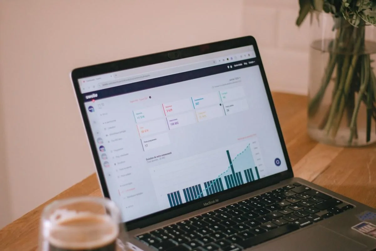 A laptop displaying a marketing dashboard on a wooden workspace, photographed by Swello.