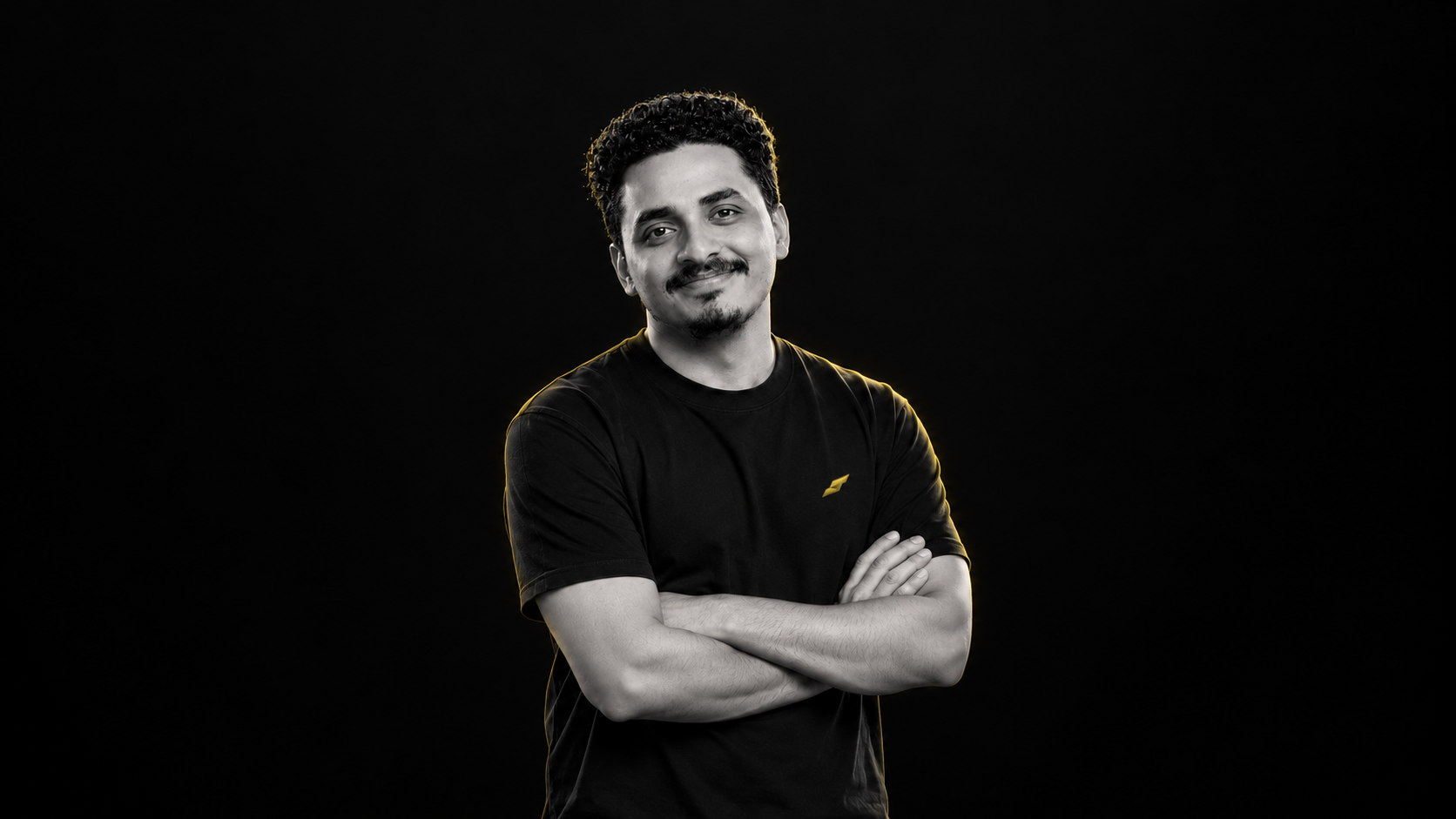 Ahamed Suhail in a black T-shirt with crossed arms, photographed in greyscale